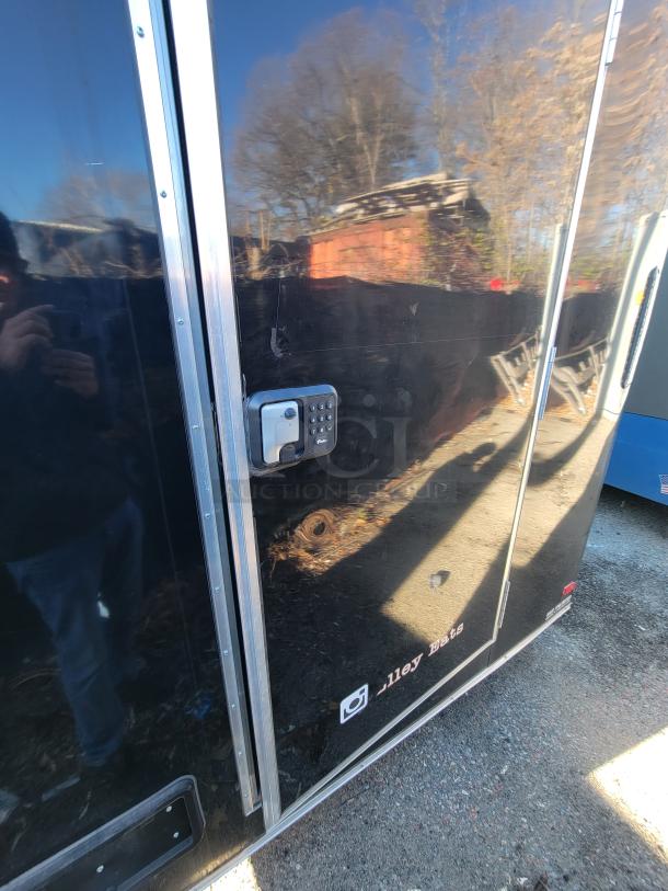 2021 16' Covered Wagon mobile food trailer with keyless entry, in excellent condition. Reflection visible on black exterior.