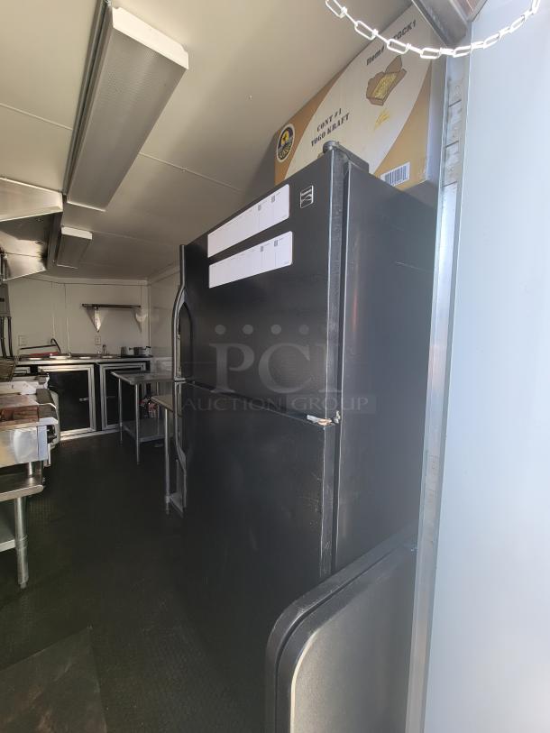 Interior of a 2021 Covered Wagon 16' mobile food trailer featuring a Kenmore fridge/freezer combo, non-slip flooring, and prep tables.