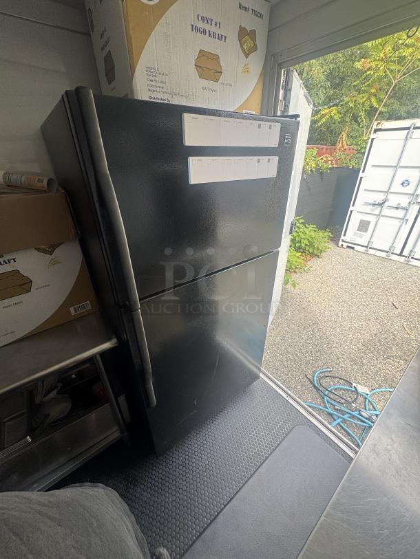 Kenmore fridge/freezer in a 2021 mobile food trailer by Covered Wagon. Boxed items on top; non-slip floor visible.