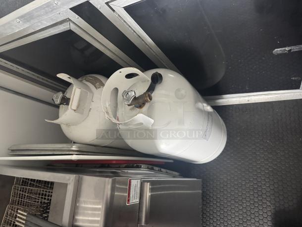 Interior view of a 2021 Covered Wagon mobile food trailer with two white 40LB propane tanks on non-slip flooring.