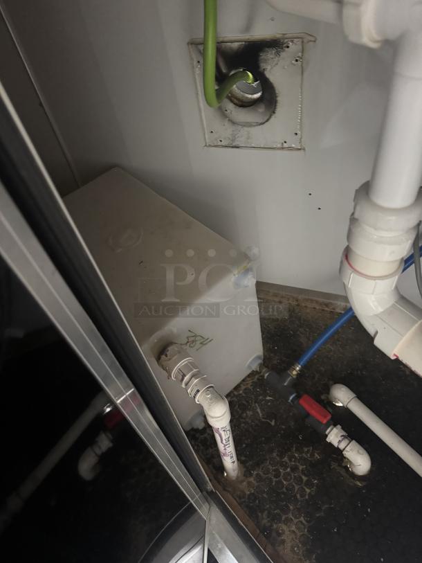 Utility area of a mobile food trailer showing pipes, a Bosch water heater, and connections, indicating plumbing setup.