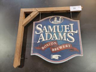 Samuel Adams Boston Brewery hanging wood sign, 24-inch, double-sided shield with logo, suspended by metal chains from rustic mount.