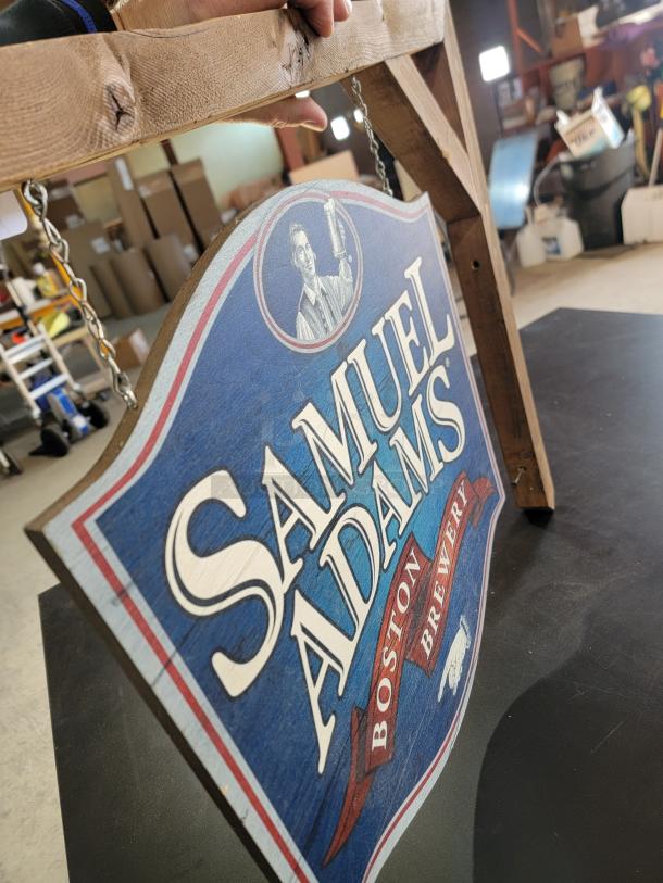 Samuel Adams Boston Brewery hanging wood sign, 24", brand-new. Features Sam Adams logo on double-sided shield, metal chains, rustic wood mount.