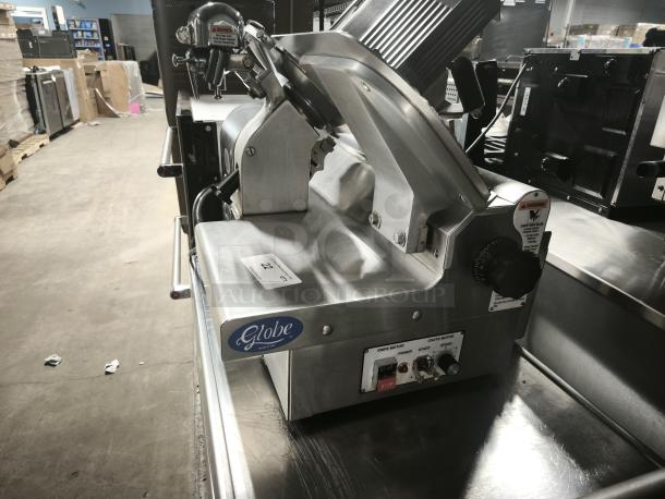 Brand new Globe 3875V 12" commercial meat slicer, featuring stainless steel body, control knobs, and warning labels.