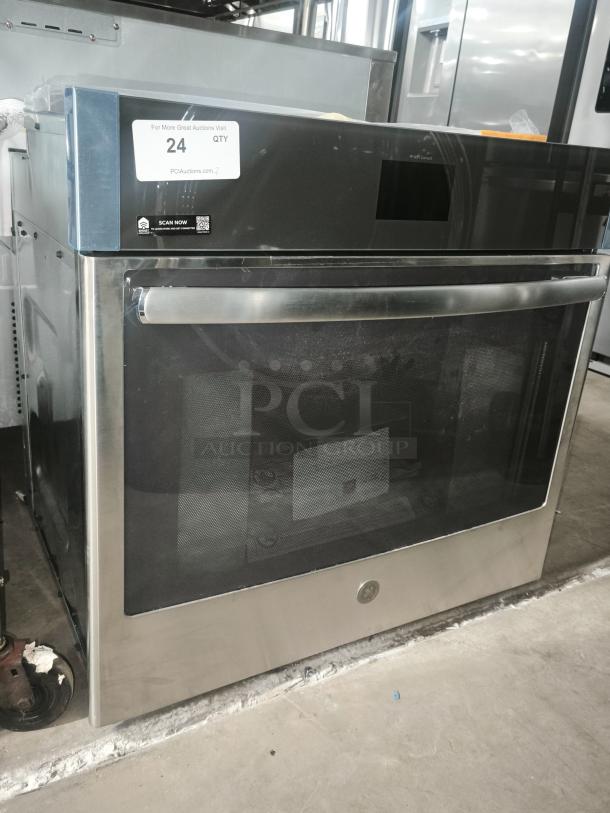 Brand new stainless steel oven with digital display panel, large front window, and sleek handle. Auction tag indicates item is unit 24.