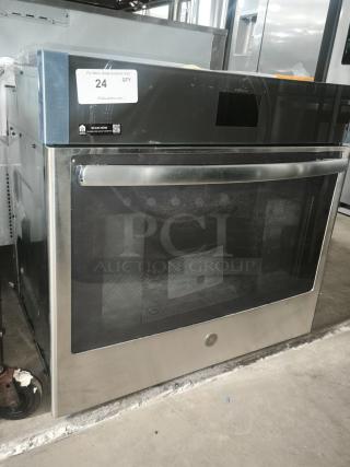 Brand new stainless steel oven with digital display panel, large front window, and sleek handle. Auction tag indicates item is unit 24.