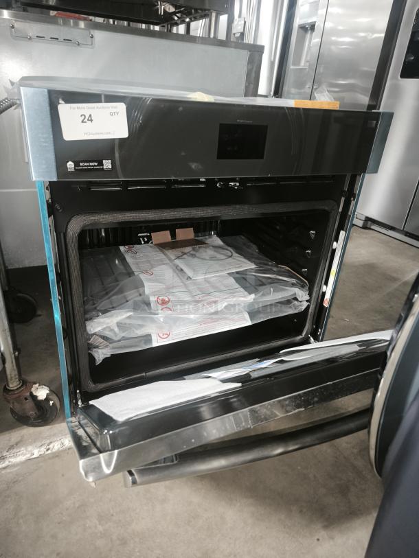Brand new black wall oven, open door showing interior. Tags indicate quantity of 24. Untouched condition with packaging inside.