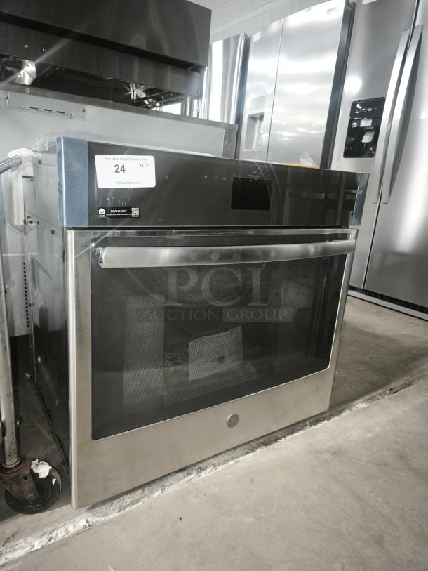 Brand new stainless steel oven, modern design, digital display. Visible tags indicate item is unused, marked "24 QTY".