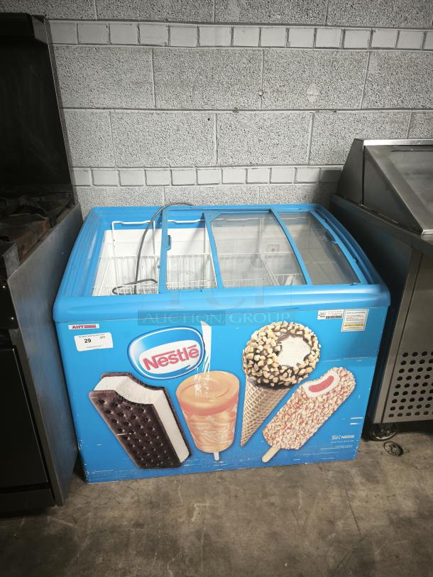 AHT RIO S 100 commercial chest freezer with Nestle branding. Missing right-side glass pane. 115 volts, 1 phase, tested working.