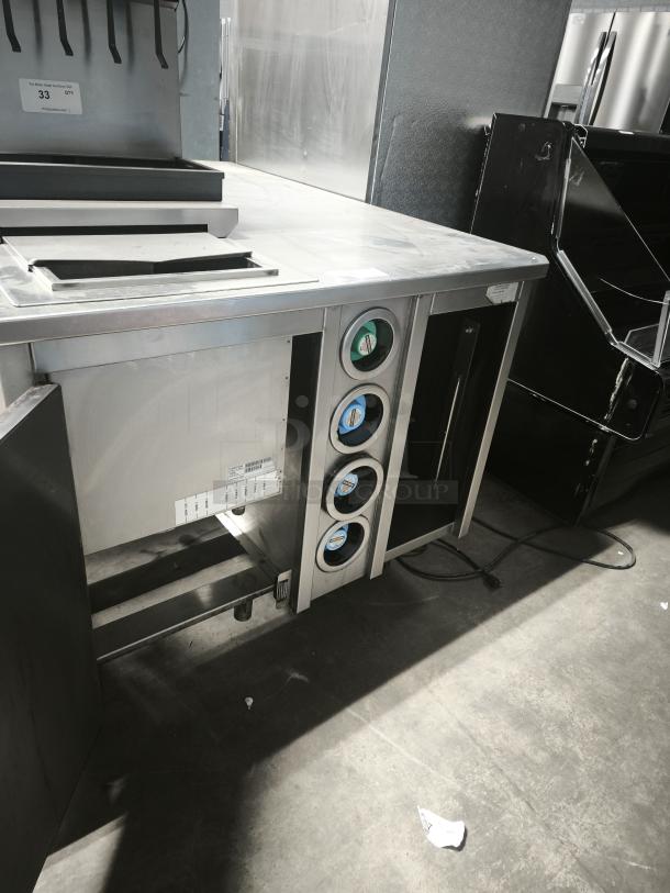S&G Manufacturing BC7-1543 custom corner stainless steel table in good condition, features multiple dispensers.