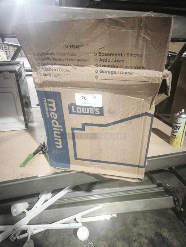 Cardboard box labeled "Lowe's" for household items, slightly open, on a metal shelf. Box condition appears used.