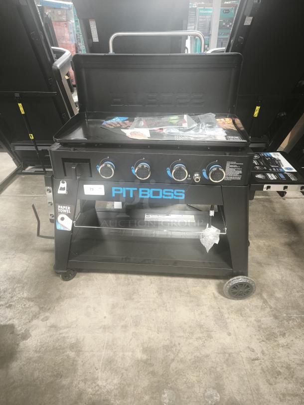 Brand new Pit Boss Ultimate 4-Burner Lift-Off Griddle, model 10782, shown with lid open. Features include multiple burners and storage shelf. Tags indicate paper towel holder.