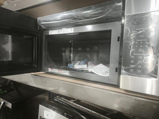 Brand new GE JVM7195SK6SS 1.9 cu. ft. over-the-range microwave oven, stainless steel, open door showing interior, protective film intact.