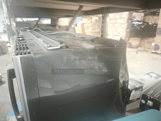 Brand new GE 1.9 Cu. Ft. over-the-range microwave oven, model JVM7195SK6SS. dent on side panel, visible in warehouse setting.