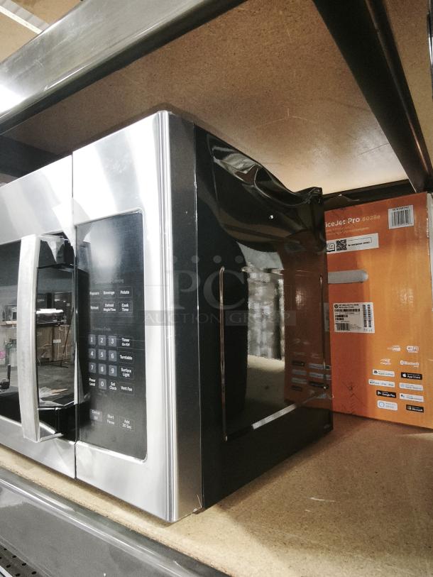 Brand new GE 1.6 Cu. Ft. Over-the-Range Microwave, model JVM3162RJ6SS, stainless steel finish, on shelf.