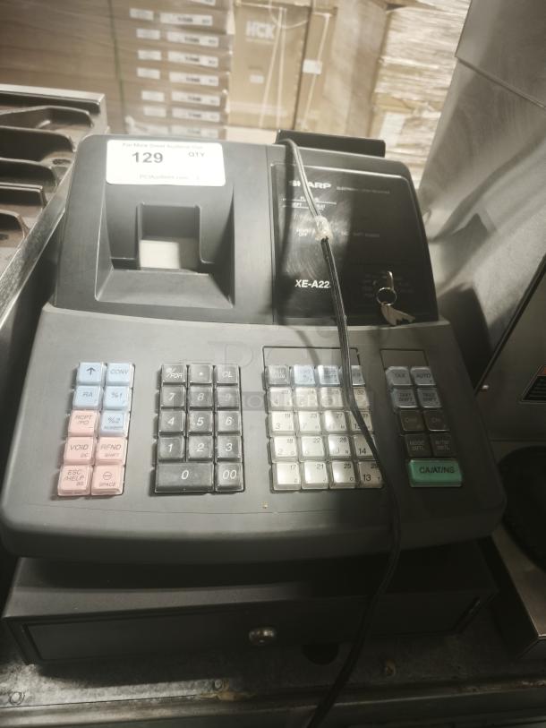 Sharp XE-A22S cash register, 14x14x12 inches, in used condition. Features numeric keypad, receipt print slot. Visible auction tag.