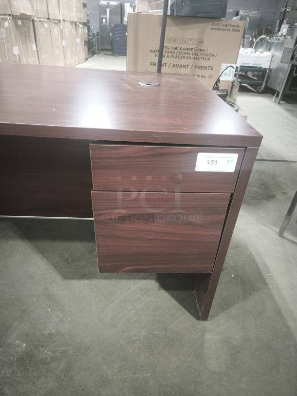 10500 Series Left Return Pedestal Desk in wood finish, two drawers, cable grommet hole, auction lot label visible, good condition.