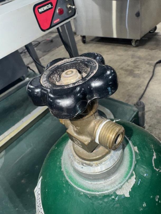 60 cuft aluminum oxygen cylinder with a green top, brass valve, and visible wear. Markings indicate pressure specifications.