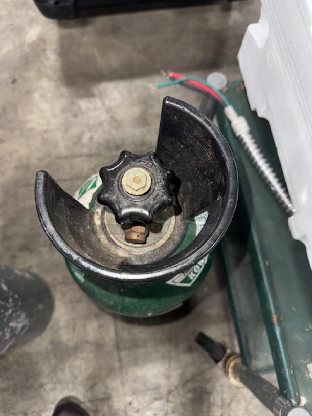 60 cuft aluminum oxygen cylinder, green, with black valve cover. Shows signs of use; key for medical or industrial use.