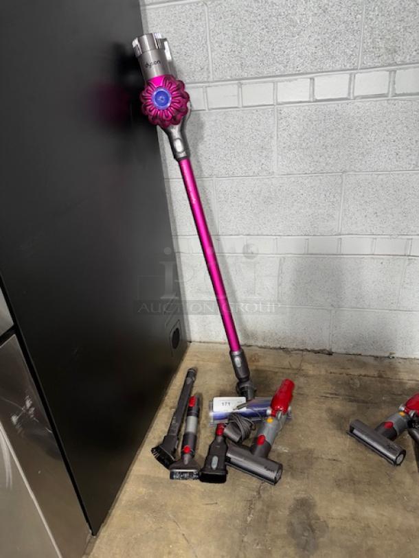 Dyson V11 Torque Drive cordless vacuum with accessories, purple, tested and working, leaning against a wall.
