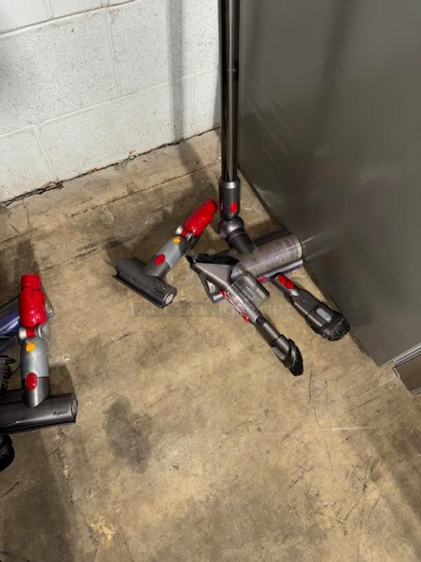 Dyson V11 Torque Drive cordless vacuum with multiple attachments, in gently used condition, shown on concrete floor.