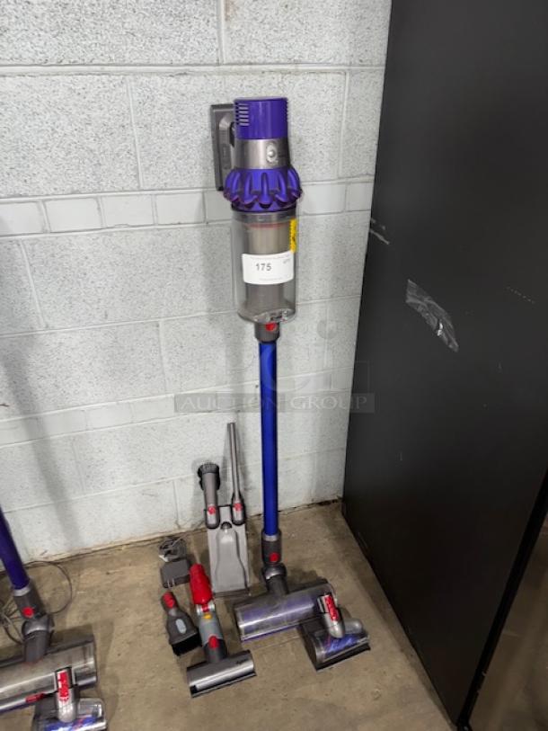 Dyson V11 Torque Drive cordless vacuum in purple, displayed upright with multiple attachments, label reads "175".