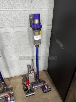 Dyson V11 Torque Drive cordless vacuum in purple, displayed upright with multiple attachments, label reads "175".