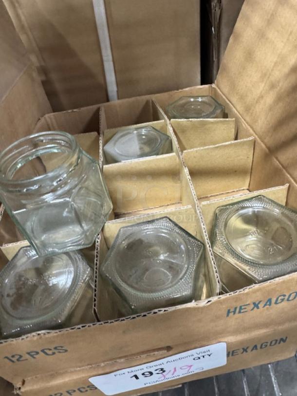 12 new 1.5 oz hexagon glass jars in box, each with clear glass and pristine condition, ideal for storage or crafts.