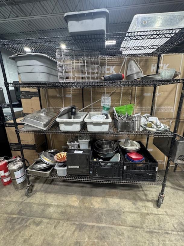Metal shelving unit filled with assorted kitchenware items, including trays, bins, bowls, utensils, and containers. Varied condition.