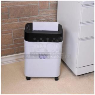 A paper shredder next to a brick wall and white cabinet, positioned on a beige carpet.
