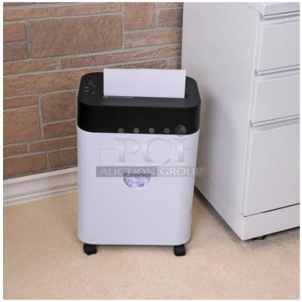 A white and black paper shredder on wheels beside a white cabinet. Features a sheet of paper partially inserted on top.