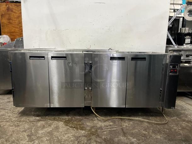 4-door stainless steel pizza prep table, used, with sturdy build and integrated controls; ideal for restaurant kitchens.