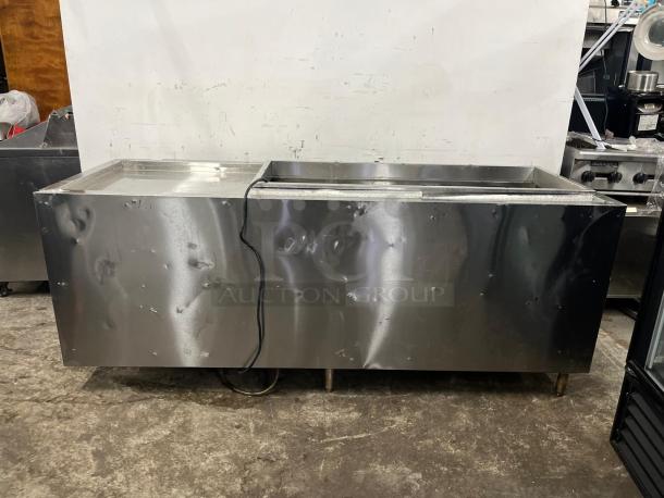 Industrial 4-door pizza prep table, stainless steel, visible dents, no labels, moderate wear, essential for kitchen use.