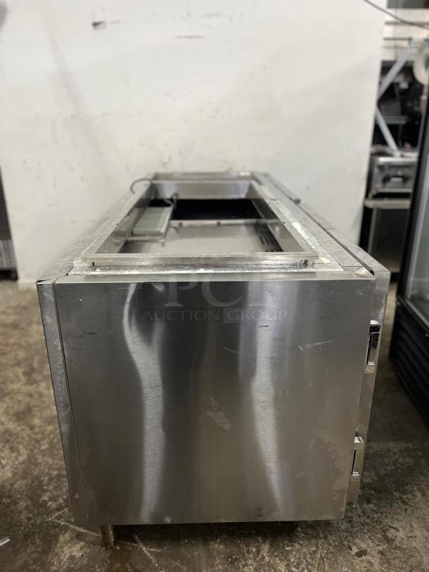 Four-door stainless steel pizza prep table in used condition, showing surface wear. Features durable construction for commercial use.