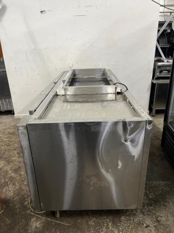 4-door stainless steel pizza prep table, dents on front, cord visible. Perfect for commercial kitchen, spacious design.