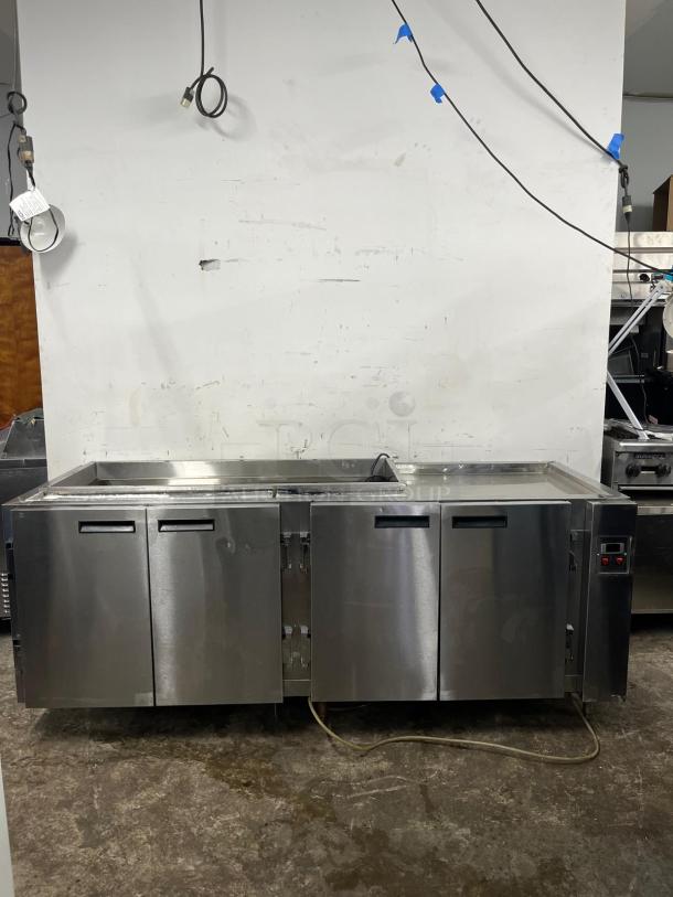 Four-door stainless steel pizza prep table, features refrigeration controls. Appears in good condition with a clean surface.