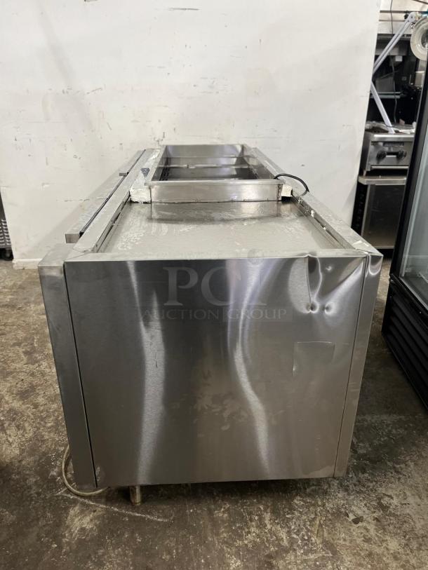 4-door stainless steel pizza prep table, used condition. Features include a spacious top surface and built-in pan slots.