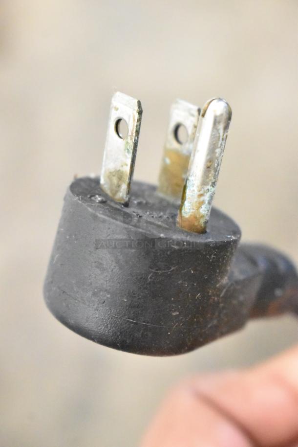 Close-up of a power plug, likely for the 2019 Delfield 406P-STAR2 cooler, showing three prongs with slight oxidation.