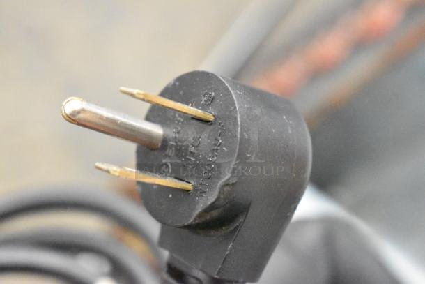 Close-up of a black electrical plug for the 2020 Delfield 406P-STAR2 cooler, showing prongs and manufacturer's labeling.