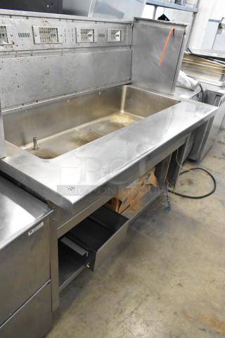 Stainless steel commercial steam table with open compartments and visible wiring. Signs of use on surface.