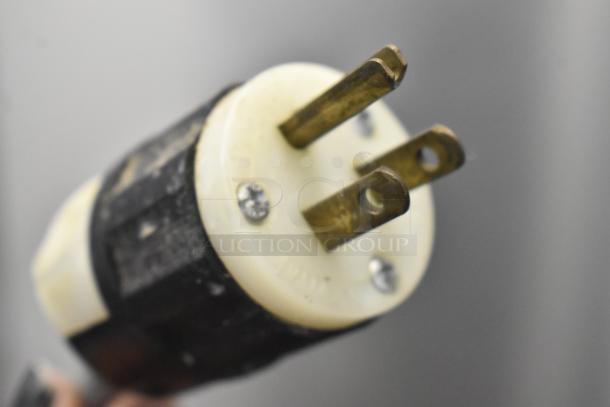 Close-up of a 3-prong electrical plug related to the Ricemini RM-401AG rice washing machine showing metal prongs on a plastic base.