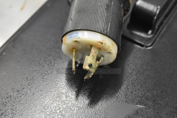 Close-up of a worn electrical plug with visible corrosion on metal prongs. Plug end labeled HBL2621 30A 250V.