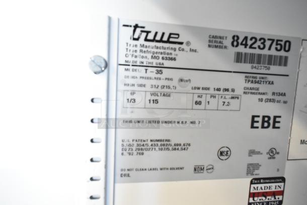 True T-35 stainless steel commercial cooler, 2-door, poly coated racks, on casters. Voltage: 115, 1 Phase. Model tag visible.