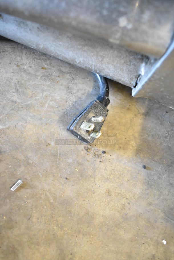 Broken power plug of 2017 True T-35 Stainless Steel Commercial Cooler on concrete floor, indicating repair need.