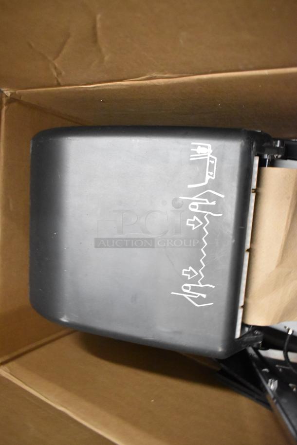 Lot of miscellaneous items in box, featuring a black paper towel dispenser with icons, moderate wear.