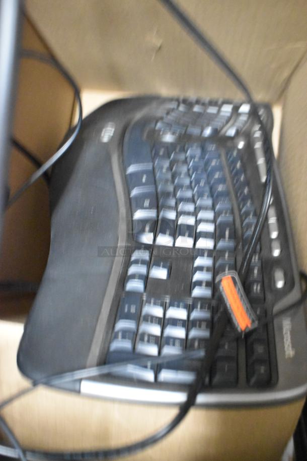 Blurred image of a Microsoft keyboard with visible cables, part of a lot including a paper towel dispenser and trash can.