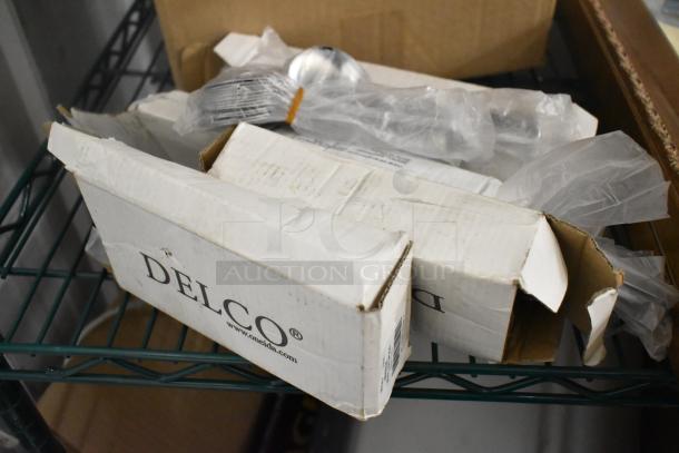 Two-tier lot with DELCO branded boxes containing dinner knives. Items include framed pictures. Box condition is worn.