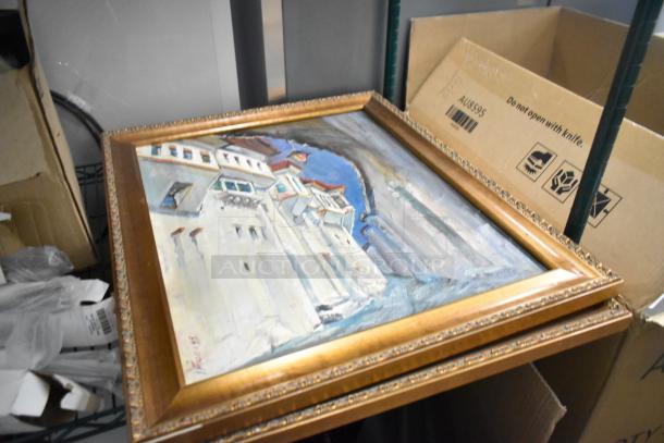 Framed painting of a cityscape with ornate gold trim, placed in storage with cardboard boxes and dinner knives.