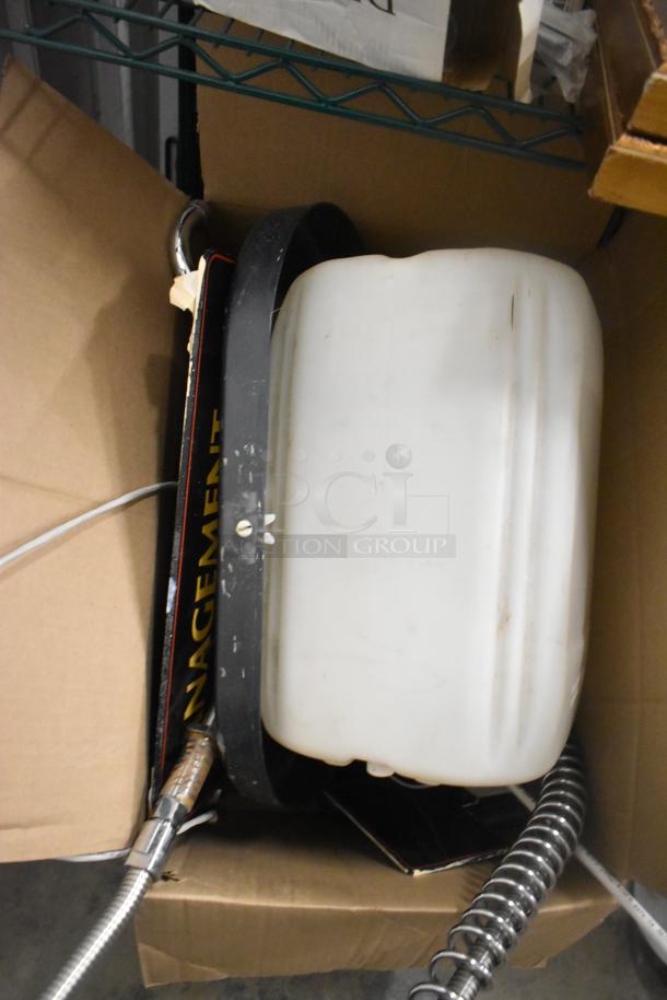 Two-tier auction lot with a white plastic container, metal hose, and partial "MANAGEMENT" sign in a box. Condition unknown.