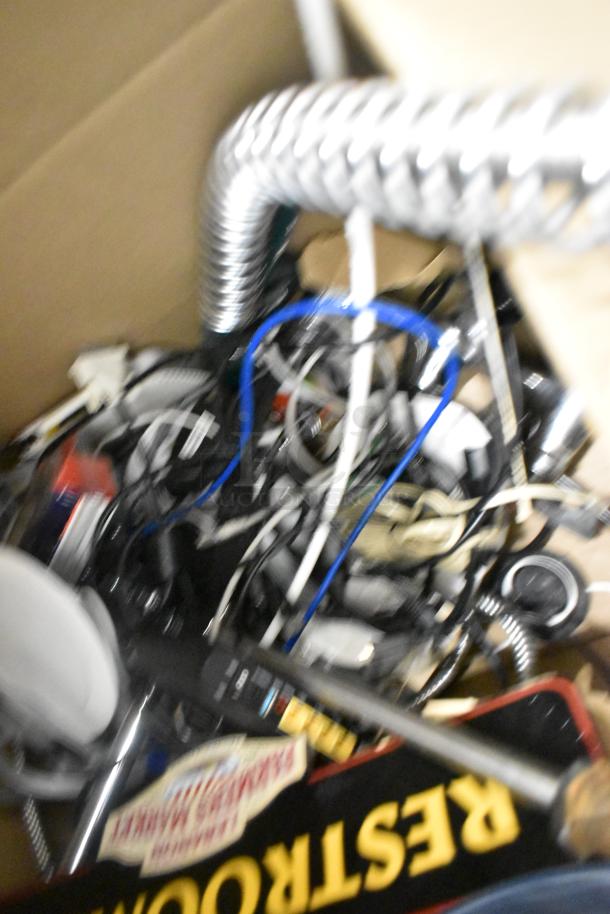 Box of assorted items including cables, a flexible metal tube, and a tray marked "Restaurant." Condition unclear.
